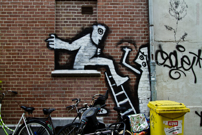 zugemauertes Fenster, Backsteingebäude mit einem Grafiti: Eine Figur steigt aus dem nicht vorhandenen Fenster auf eine Leiter.