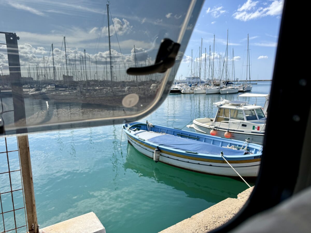 Ausblick aus dem Campervan-Fenster direkt in Hafenbecken. Grünes Wasser. mehrere Fischer- und Segelboote